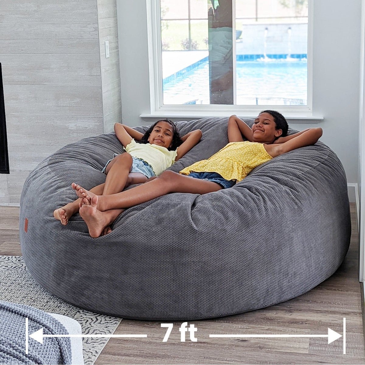 True 7-foot giant round bean bag with two kids relaxing together